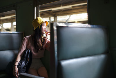 Woman looking through window while sitting in train