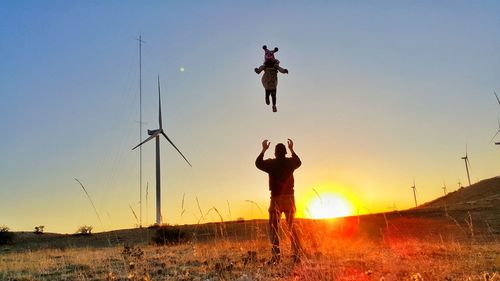 Silhouette man standing on field against sky during sunset