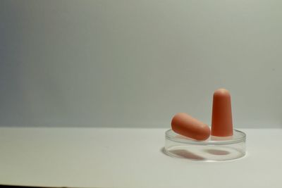 Close-up of orange candle on white table