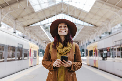 Full length of young woman using phone while standing on bus