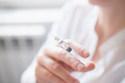 Midsection of woman holding syringe