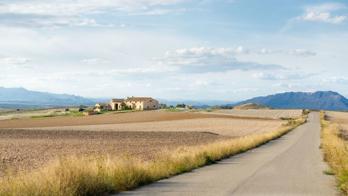 Road amidst field against sky