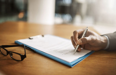 Midsection of doctor writing in book