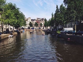 Boats on canal amidst trees against sky