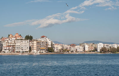 Buildings by sea against blue sky