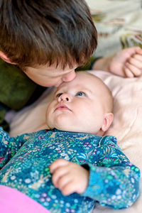 Brother of five years and a sister of three months are lying on the bed. top view.