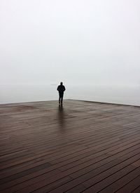 Full length of man standing on pier against clear sky