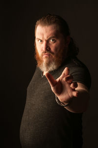 Portrait of man standing against black background