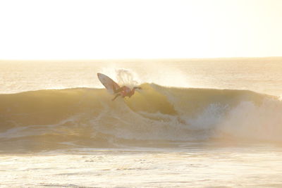 Man surfing in sea against clear sky