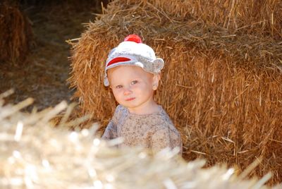 Portrait of boy sitting by hay bales