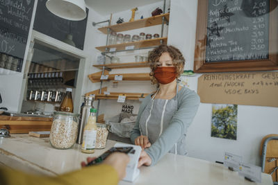 Mature customer paying through smart phone in zero waste store during covid-19