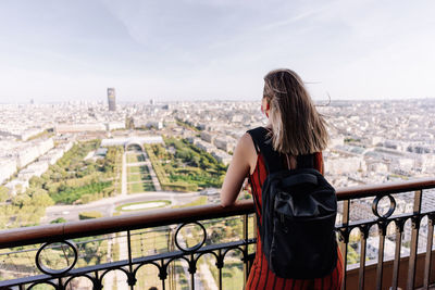 Woman standing on balcony with cityscape in background