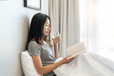 Young woman using mobile phone while sitting at home