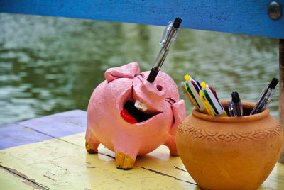 Pink pig smiles face  pen holder  is on wood  table. pen  in  nose's  pig.   stationery design.