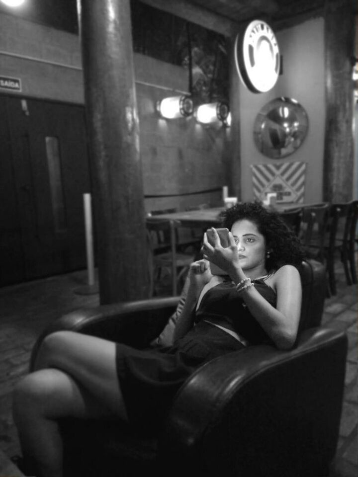 YOUNG WOMAN SITTING ON TABLE AT KITCHEN