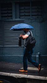 Full length of man holding umbrella on street