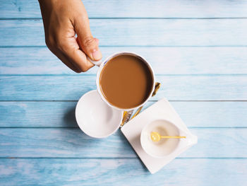 Midsection of person holding coffee cup on table