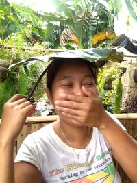 Portrait of girl holding plant against trees
