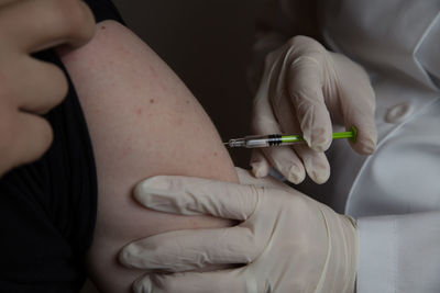 Midsection of doctor injecting syringe to patient against gray background