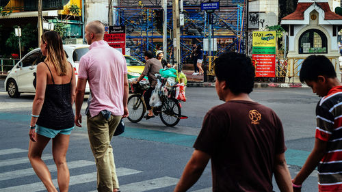 Rear view of people walking on street in city