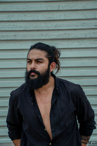 Man looking away while standing against wall