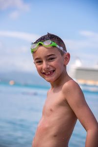 Portrait of happy boy standing on beach against sky