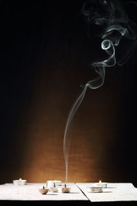 Close-up of smoke emitting from table against black background