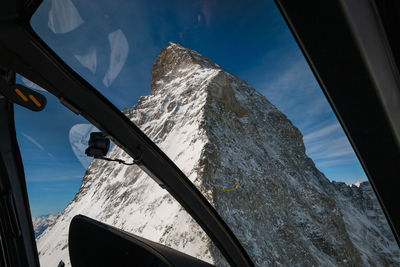 Scenic view of snowcapped mountains against sky seen through window