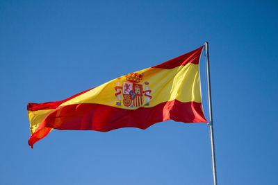 Low angle view of spanish flag against blue sky