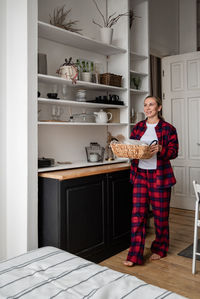 An attractive young woman with a basket in her hands cleans up her cozy kitchen. home style concept