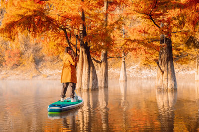 Rear view of woman in boat in lake during autumn