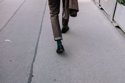 Low section of man walking on road