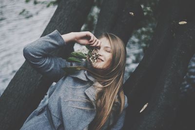 Close-up of smiling young woman against tree trunk