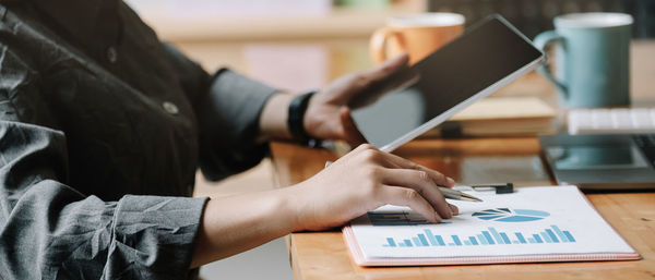 Midsection of businesswoman using digital tablet