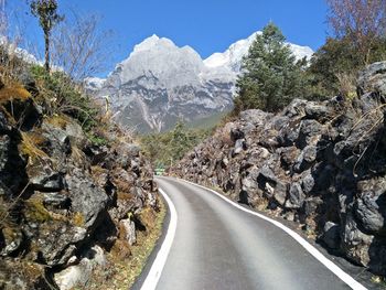 Road amidst trees and mountains against sky