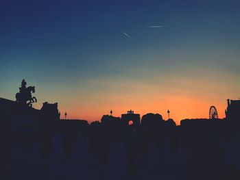 Silhouette built structure in city against sky during sunset