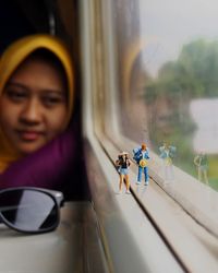 Young woman looking at hiker figurines on window sill in train