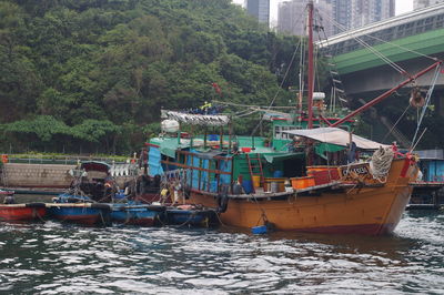 Fishing boats sailing on river by trees