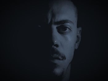 Close-up portrait of man against black background