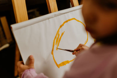 Cropped hand of woman painting on table