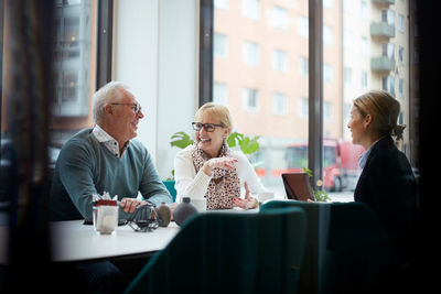 Smiling senior couple talking while sitting with realtor in office