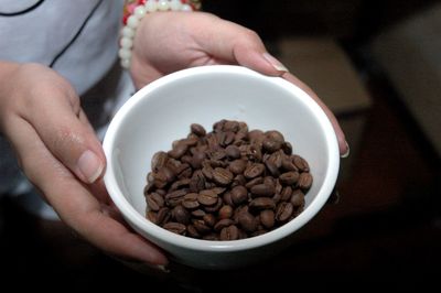 Midsection of woman holding coffee beans in cup