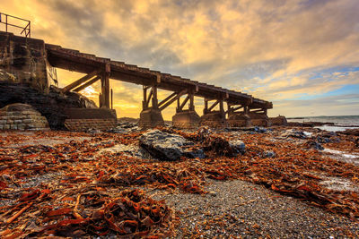 Bridge over sea against sky during sunset