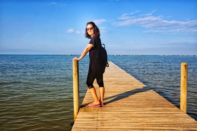 Full length of woman standing on pier over sea against sky