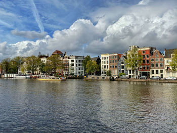 Buildings by river against sky