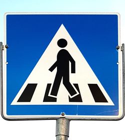 Close-up of road sign against blue sky