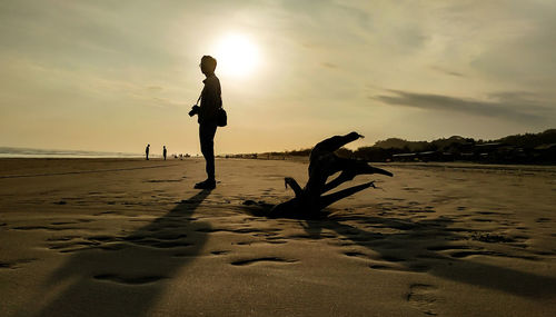 Silhouette man standing at beach against sky during sunset