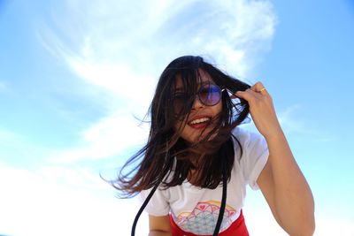 Low angle portrait of woman standing against sky