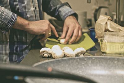 Midsection of man cutting mushrooms on table at home