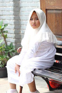 Portrait of girl in hijab sitting on bench